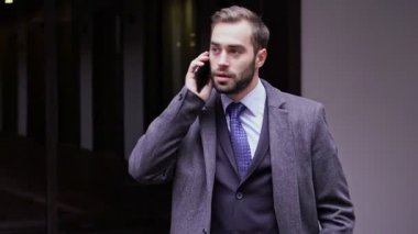 Şehirde açık havada dururken akıllı telefon ile konuşurken ceket gülümseyen yakışıklı iş adamı