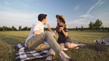 Genç mutlu sevgi dolu çift birbiriyle konuşurken şarap içme alanında piknik açık havada oturan