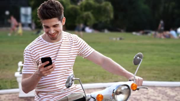 スクーターで屋外で携帯電話を使用して幸せな男 — ストック動画