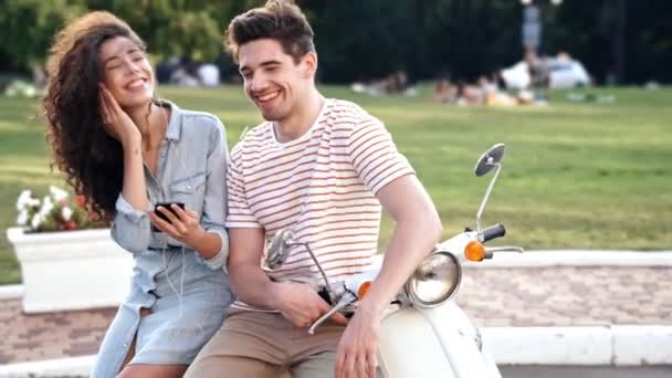 Glückliches Romantisches Paar Das Auf Einem Roller Sitzt Und Handy — Stockvideo