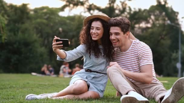 Glückliches Romantisches Paar Sitzt Gras Und Macht Ein Selfie Mit — Stockvideo