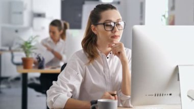 Genç memnun konsantre kadın meslektaşının belgelerine bakarak pc bilgisayar kullanarak ofiste çalışan