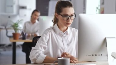Genç güzel mutlu kadın meslektaşının belgelerine bakarak pc bilgisayar kullanarak ofiste çalışan