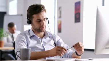 Çağrı merkezinde çalışan ve abone ile kulaklıkla konuşan güler yüzlü kendine güvenen adam