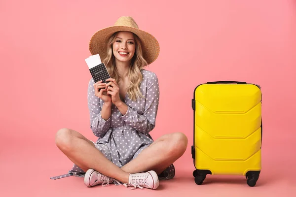 Emocionado jovem bonita turista posando isolado sobre fundo de parede rosa com mala segurando passaporte com bilhetes . — Fotografia de Stock