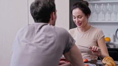 Gülümseyen sevgi dolu çift yemek yiyor ve mutfakta otururken şarap içiyor