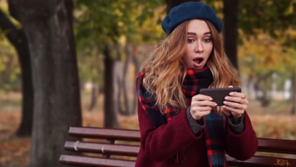 Parkta Bankta Otururken Akıllı Telefon Üzerinde Oynayan Bere Şapka Ceket — Stok video