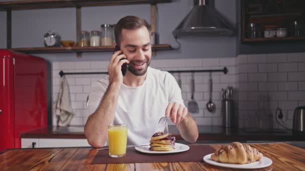 Smiling Handsome Bearded Man Having Breakfast Talking Smartphone While Sitting — Stock Video