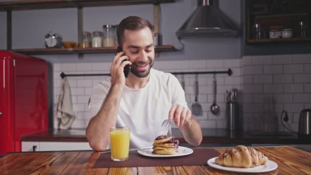 Mosolygó Csinos Szakállas Férfi Amelynek Reggeli Beszélő Smartphone Ülve Asztal — Stock videók