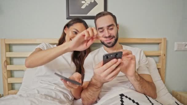 행복한 사랑스러운 부부는 침실에서 침대에 누워있는 스마트 사용하여 — 비디오