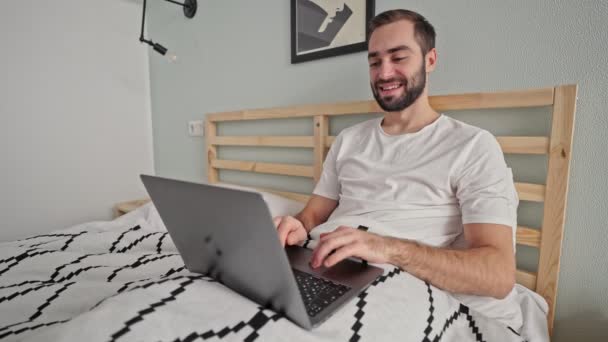 Glücklicher Bärtiger Mann Benutzt Laptop Während Schlafzimmer Auf Dem Bett — Stockvideo