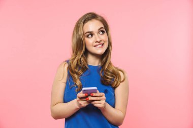 Güzel mutlu genç güzel kadın cep telefonu kullanarak pembe duvar arka plan üzerinde izole poz.
