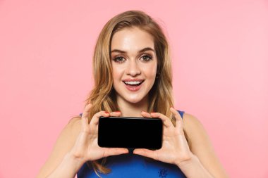Güzel kadın boş ekran gösteren cep telefonu kullanarak pembe duvar arka plan üzerinde izole poz.