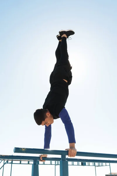 Foto de deportista haciendo acrobacias en barra de gimnasia horizontal —  Fotos de Stock