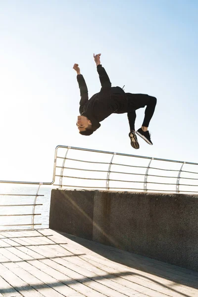 Photo of athletic man doing acrobatics and jumping during mornin — Stock Photo, Image