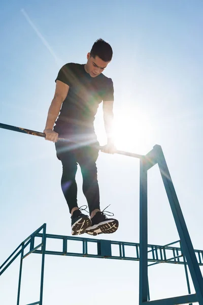 Foto de un tipo fuerte haciendo acrobacias en la barra de gimnasia horizontal —  Fotos de Stock