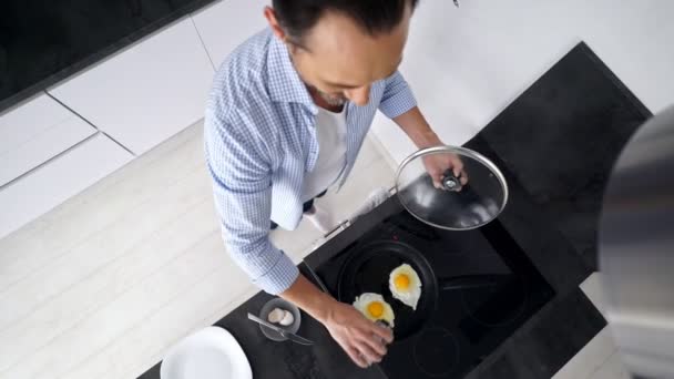 自宅の台所に立ちながら朝食を調理する成熟した男のトップビュー — ストック動画