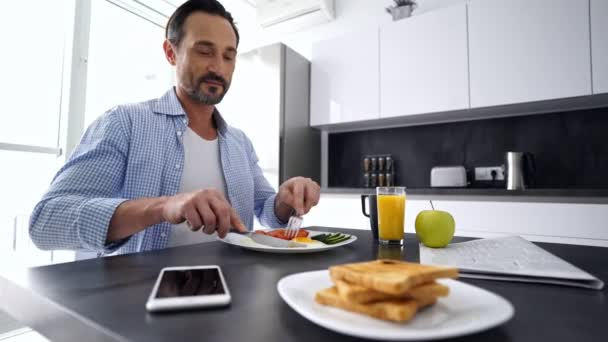 Ler Mogen Man Med Välsmakande Och Hälsosam Frukost Vid Köksbordet — Stockvideo