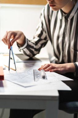 Avrupalı kadın mimarın pusula ile çizim yapıp işyerinde otururken çekilmiş makro fotoğrafı