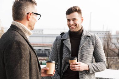 Palto giyen iki yakışıklı adam vakit geçiriyor