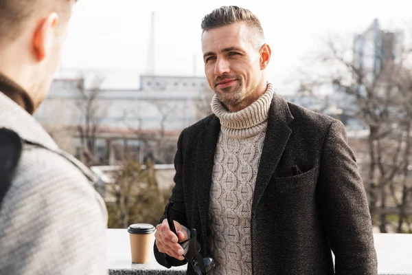 Two handsome men wearing coats spending time — Stock Photo, Image