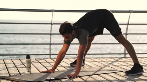 Vista Lateral Jovem Desportista Concentrado Fazendo Exercício Ginástica Perto Mar — Vídeo de Stock