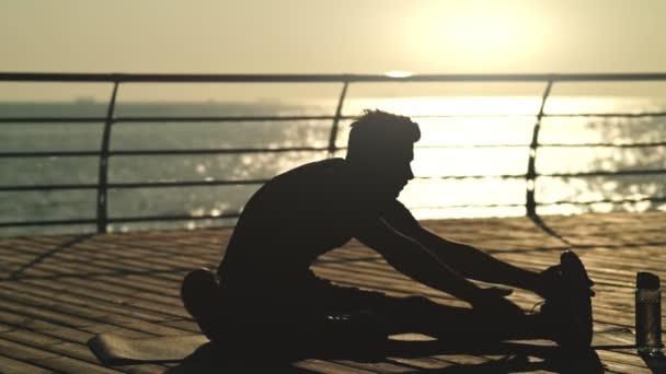 平静的年轻运动员在海边的垫子上热身的剪影 — 图库视频影像