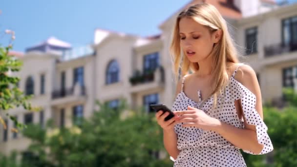Akıllı Telefon Kullanarak Elbise Mutlu Sarışın Kadın Parkta Yürürken Biriyle — Stok video
