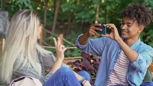 Jovem Feliz Casal Multiétnico Divertindo Com Smartphone Enquanto Passam Tempo — Vídeo de Stock