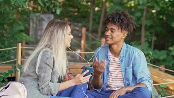 Agradable Joven Pareja Multiétnica Escuchando Música Por Teléfono Inteligente Disfruta — Vídeo de stock