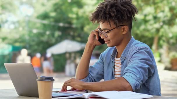 Glimlachend Afrikaanse Student Brillen Praten Met Smartphone Terwijl Zittend Bij — Stockvideo