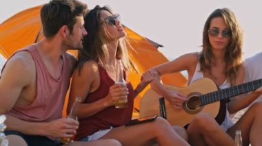 Şarkı söyleyen ve denize yakın plajda birlikte eğlenen genç komik arkadaşlar grubu