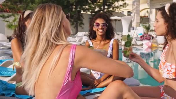 一群穿着泳衣的美女朋友在游泳池附近的躺椅上一起放松 一边喝着鸡尾酒 — 图库视频影像