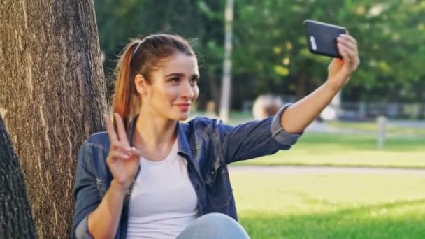 Mulher Morena Feliz Fazendo Selfie Smartphone Enquanto Senta Perto Árvore — Vídeo de Stock