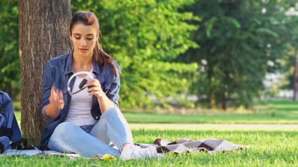 Šťastná Brunetka Poslouchá Hudbu Sluchátek Sedí Stromu Trávě Parku — Stock video