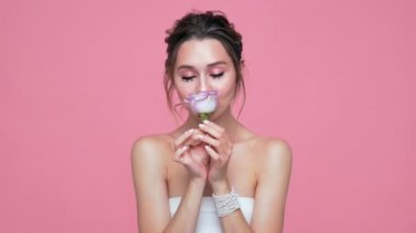 Güzellik pembe arka plan üzerinde çiçek ile poz yüzünde ve elleri inci ile esmer kadın memnun