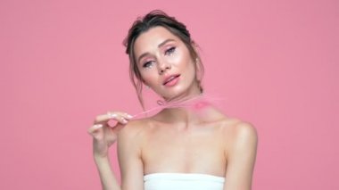 Pembe arka plan üzerinde turba ile poz yüzünde ve elleri inci ile Güzellik eğlenceli esmer kadın