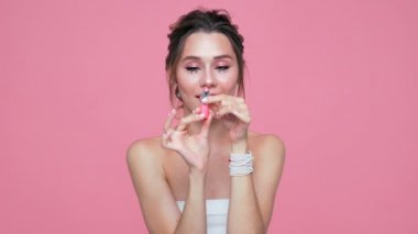 Güzellik pembe arka plan üzerinde pomade ile poz yüzünde ve elleri inci ile esmer kadın memnun