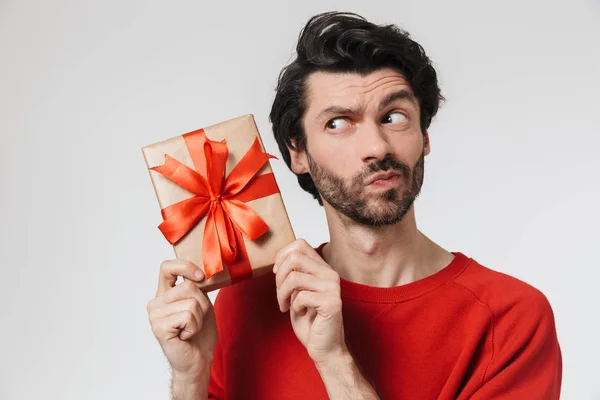 Schöner junger aufgeregter Mann posiert isoliert über weißem Wandhintergrund mit Geschenk-Box. — Stockfoto