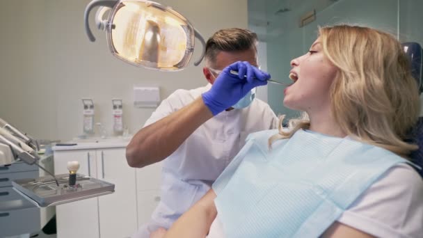 歯科医院で診察後の処置後の画面を見ながら 歯の問題について歯科医を聞く深刻なブロンドの女性 — ストック動画