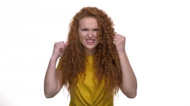 Kızgın genç kızıl saçlı kıvırcık kadın çok yüksek sesle çığlık ve beyaz arka plan izole üzerinde kameraya bakarken elleriyle gesturing