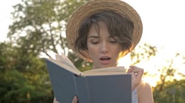 Kitap okuyan ve parkta etrafa bakan çekici gülümseyen genç kadının yakından görünümü