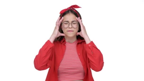 赤いシャツの疲れた若いブルネットの女の子は 孤立した白い背景の上にカメラを見ながら 彼女の寺院をマッサージする頭痛の原因 — ストック動画