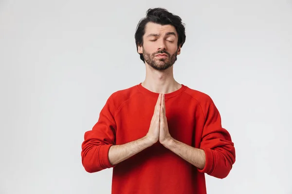 Bello giovane uomo concentrato posa isolato su sfondo bianco parete meditare . — Foto Stock