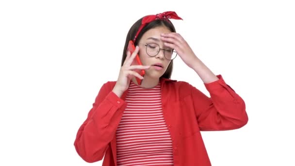 不高兴的年轻黑发女孩在红色衬衫变得紧张和愤怒 而通过智能手机谈论白色背景孤立 — 图库视频影像