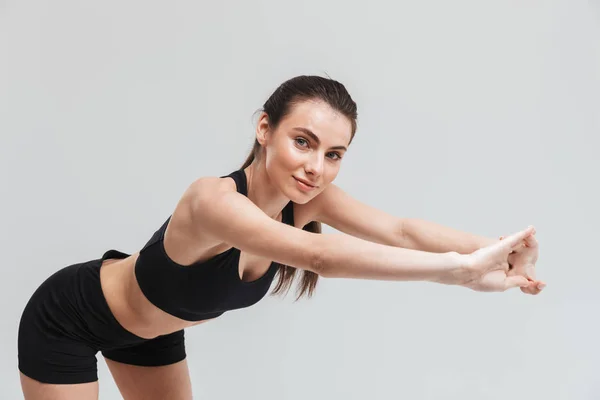 Mooie jonge sport fitness vrouw maken oefeningen geïsoleerd over grijze muur achtergrond. — Stockfoto
