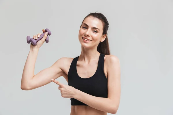 Sport-Fitness-Frau macht Übungen mit Kurzhanteln isoliert über grauem Wandhintergrund. — Stockfoto
