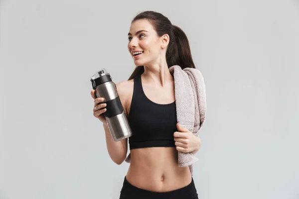 Hermosa joven deporte fitness mujer agua potable aislado sobre fondo gris de la pared . — Foto de Stock