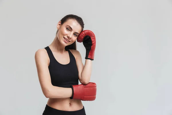 灰色の壁の背景の上に隔離された若いスポーツフィットネス女性ボクサーは、手袋で演習を行います. — ストック写真