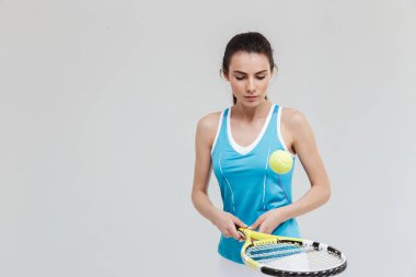 Spor fitness kadın tenisçi gri duvar arka plan üzerinde izole egzersizleri yapmak.